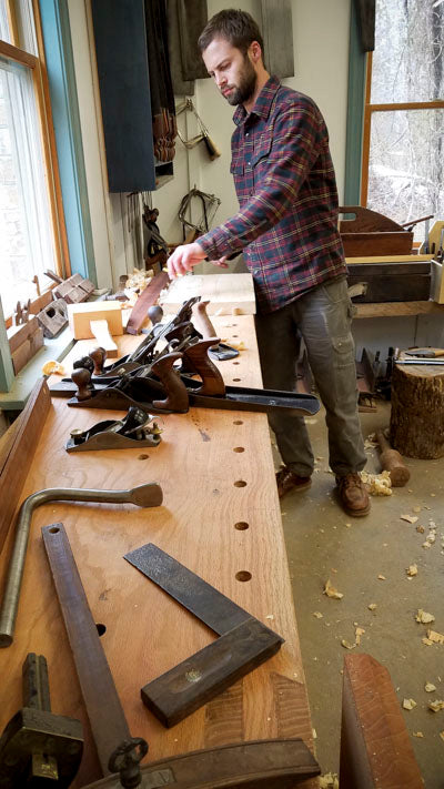 Student using hand planes on a Roubo workbench in a woodworking class