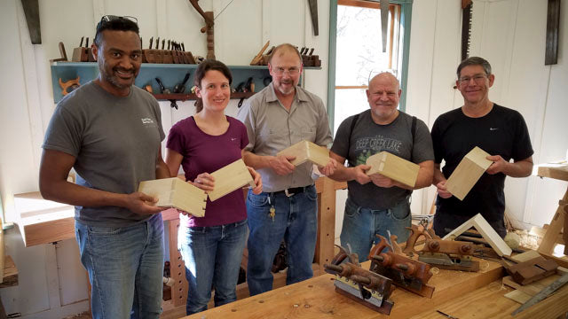 Students at the introduction to hand tool woodworking class holding a dovetail joint