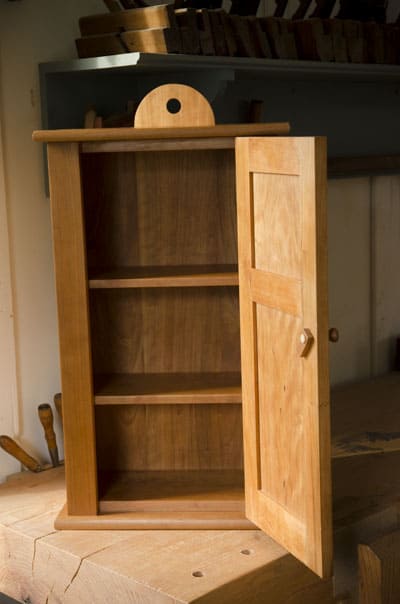 Open door of a Cherry shaker wall cupboard