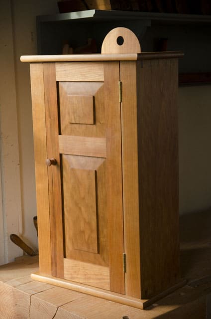 Cherry shaker wall cupboard on a woodworking bench