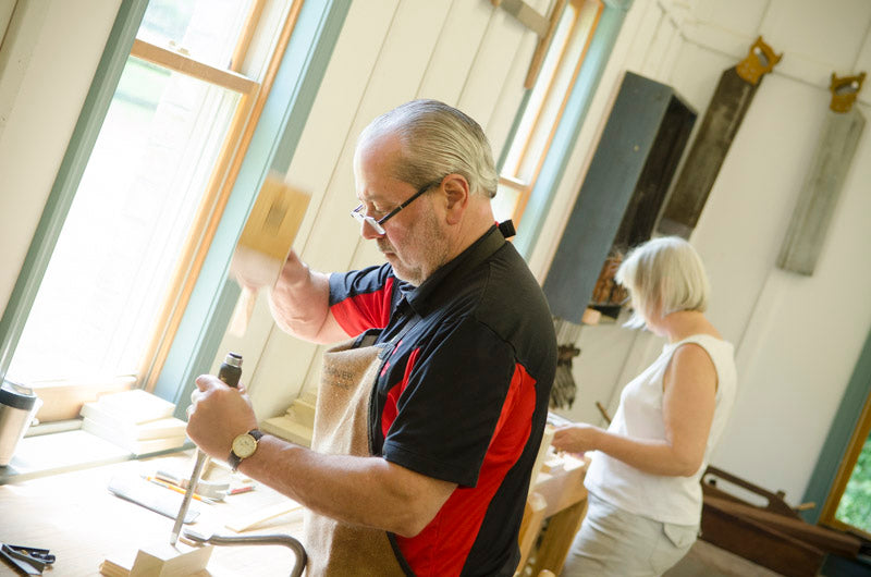 Man chopping a mortise and tenon joint using a mortise chisel and joiners mallet at a hand tool woodworking class