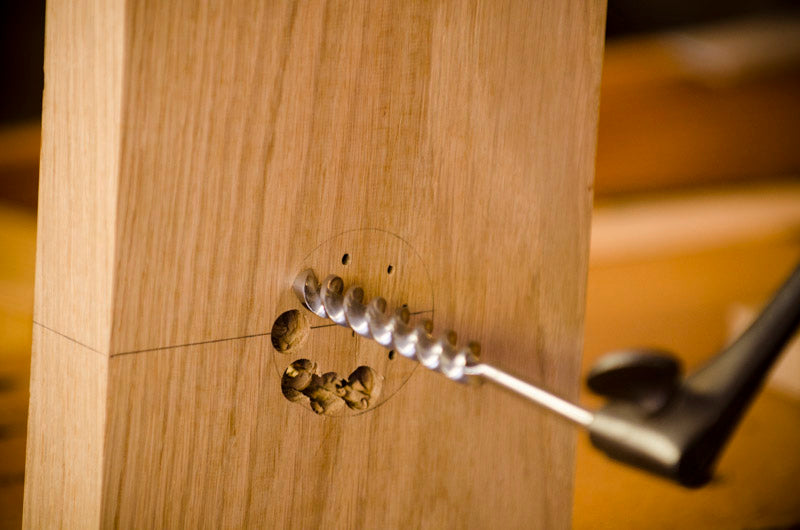 Will Myers using a brace and bit to bore holes for a Moravian workbench vise