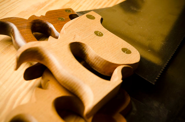 Three hand saws or panel saws sitting on a Roubo Workbench 