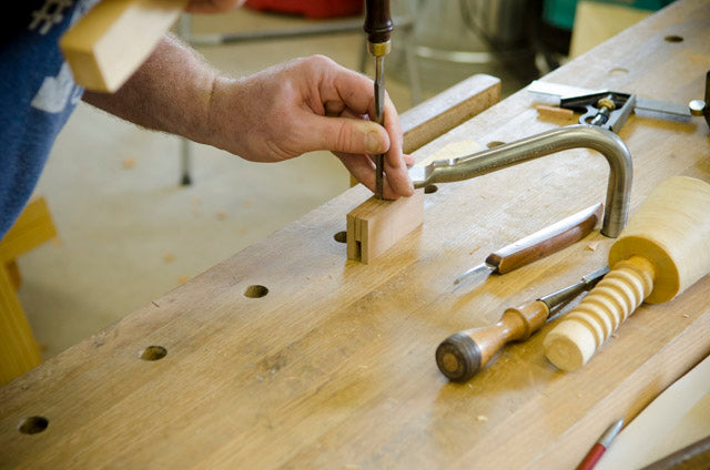 Student in a hand tool woodworking calss using a chisel and mallet to make a wooden try square