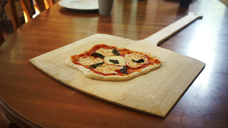 wooden pizza peel with homemade pizza