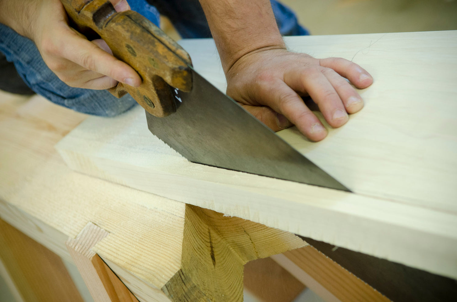 Student using a hand saw in a woodworking school