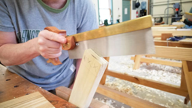 Woman cutting a mortise and tenon joint using a dovetail saw at a hand tool woodworking class