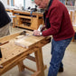 Student using a smoothing plane on a Moravian workbench in a woodworking class