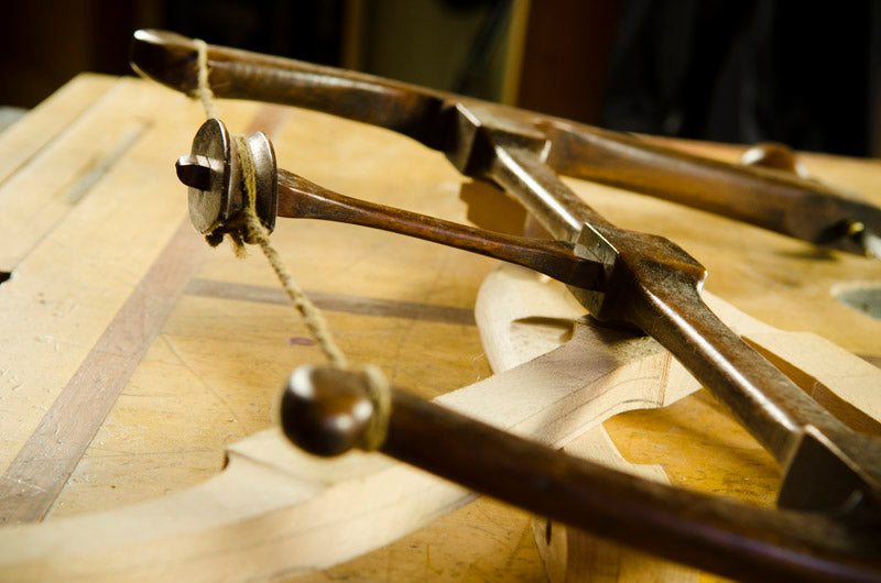 Antique Howarth Bowsaw sitting on a wood work bench with a reproduction bow saw