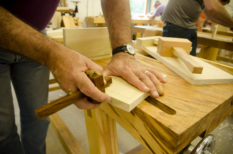 Student using a marking gauge to layout a dovetail joint on a Moravian Workbench at the introduction to hand tool woodworking class 