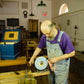 Bill Anderson using a hand crank grinder to sharpen a hand plane blade