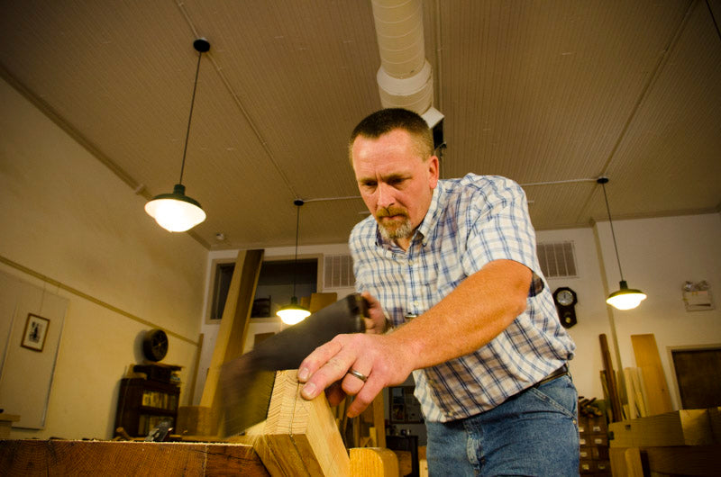 Will Myers using a  woodworking hand saw to cut the legs of a Moravian workbench