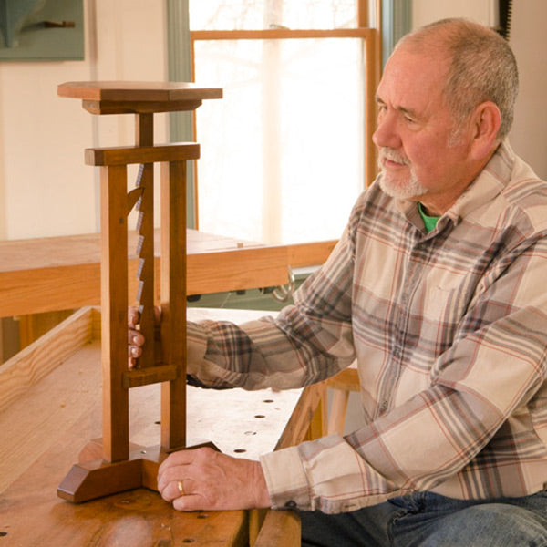 David Ray Pine looking at a ratcheting candle stand table in a woodworking school