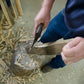 Woodworker shaping a shaving horse leg with a hatchet at a woodworking class
