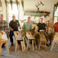 Students in a woodworking class sitting on shave horses that they just built