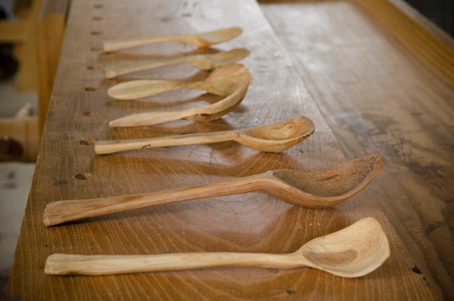 Carving wooden spoons lined up on a woodworking workbench