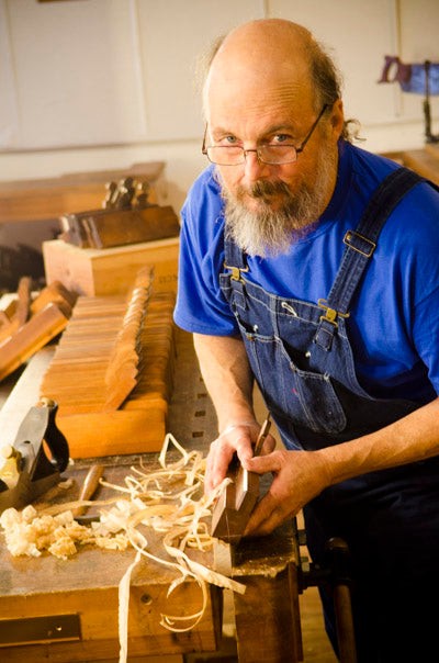 Bill Anderson using a molding plane on a woodworking workbench with hollows and rounds planes in the backgorund